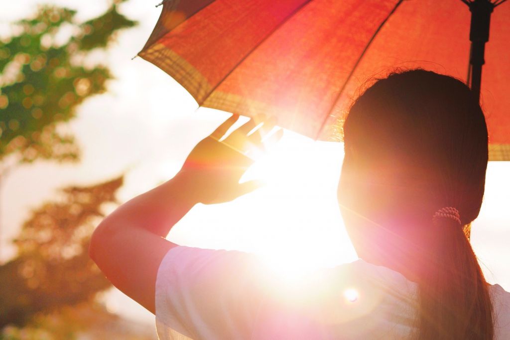 Bild zeigt eine Frau mit Sonnenschirm gegen die Sonne